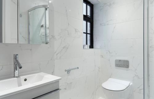 a white bathroom with a toilet and a sink at Veeve - Marylebone Mews in London