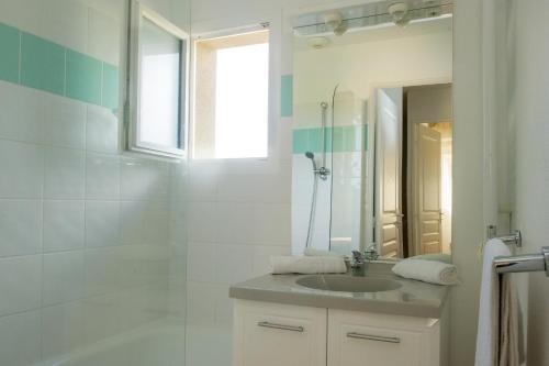 a white bathroom with a sink and a shower at Résidence Goélia Le Hameau de la Vézère in Le Bugue