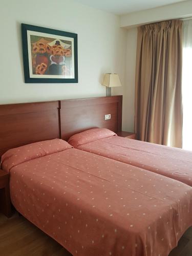 a bedroom with a bed with a red comforter at Hotel Mayna in Benidorm
