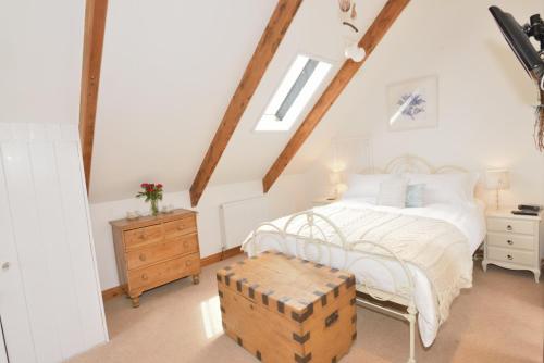 - une chambre avec un lit blanc et un coffre en bois dans l'établissement Inglenook Cottage, à Padstow