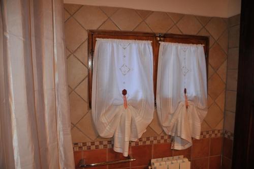 two windows in a bathroom with white curtains at "La Casa di Maria Luce" con terrazza panoramica in Gaiole in Chianti