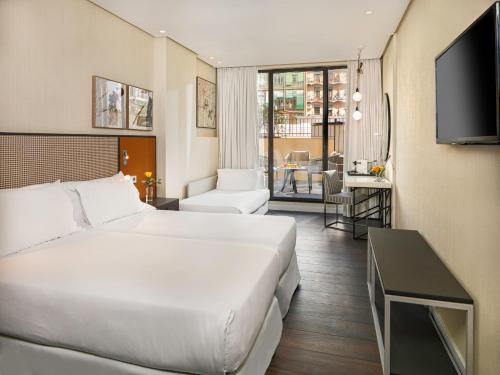 una camera d'albergo con un grande letto e una TV di H10 Art Gallery 4* Sup a Barcellona