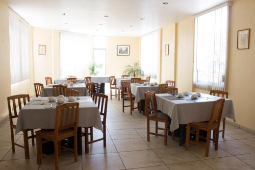 a dining room with tables and chairs and windows at Villas Hotel Cholula in Cholula