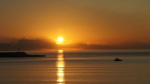 a boat in the water at sunset at Atlantida Mar Hotel in Praia da Vitória
