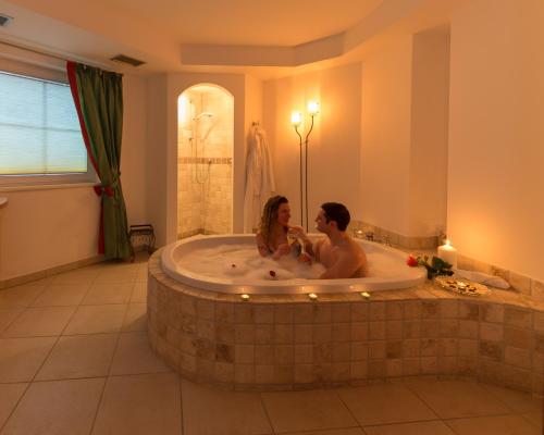 Ein Mann und eine Frau sitzen in einer Badewanne in der Unterkunft Hotel Hellweger in Sand in Taufers