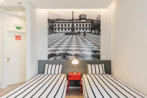 a room with two beds and a wall mural of a street at FAA Rentals 31 de Janeiro by An Island Apart in Funchal