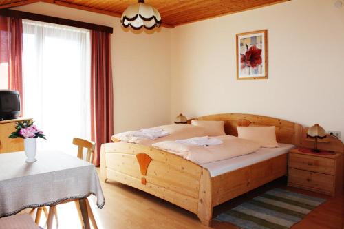 a bedroom with a wooden bed and a table at Edelweisshof in Birnbaum