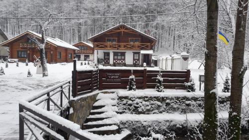 a log cabin in the snow with snow covered stairs at U Druziv in Polyana