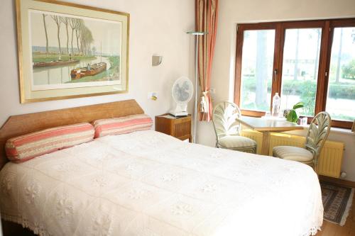 a bedroom with a bed and a table and a window at B&B Le Coquin in Bruges