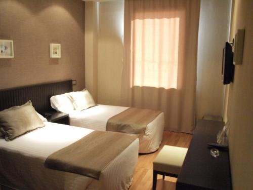 um quarto de hotel com duas camas e uma janela em Dinastia em Getafe