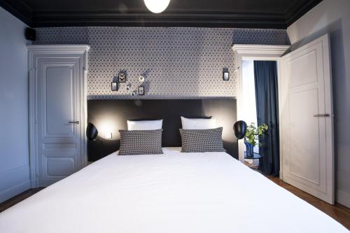 a bedroom with a large white bed with two pillows at MiHotel Gailleton in Lyon
