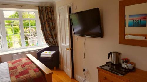 Habitación de hotel con cama y TV en la pared en The Oak at Dewlish en Dorchester