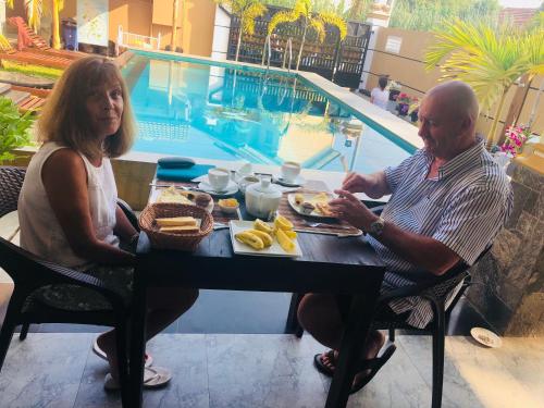 a man and a woman sitting at a table with breakfast at St CLAIRE'S GREEN Negombo Hotel & Hostels in Negombo