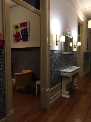 a hallway with a table and a mirror and a chair at Hotel Jardim in Coimbra