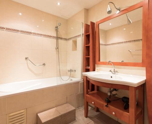 een badkamer met een wastafel, een bad en een spiegel bij Hotel de Vischpoorte, hartje Deventer en aan de IJssel in Deventer
