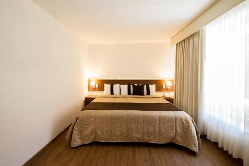 a bedroom with a bed and a large window at Quinta Rivera Hotel in Actopan