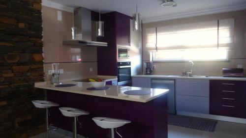 a kitchen with a counter and stools in it at Casa da Ladeira, Turismo Rural in Estreito