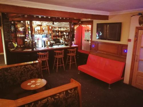 a bar with a red couch and a bar with stools at Victoria Hotel in Blairgowrie
