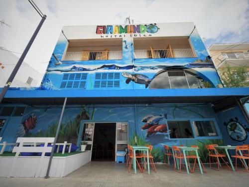 een blauw gebouw met tafels en stoelen ervoor bij Hostal Giramundo in Ibiza-stad