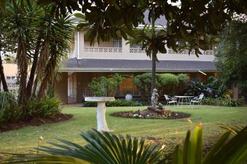 a garden with a table and chairs in front of a house at Moye Guest House in Benoni