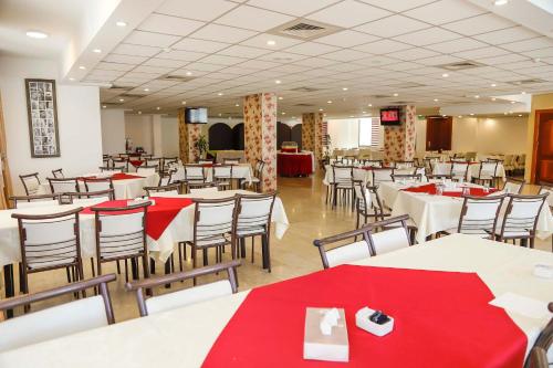 a restaurant with white tables and chairs with red napkins at City Inn Palace Hotel in Ramallah