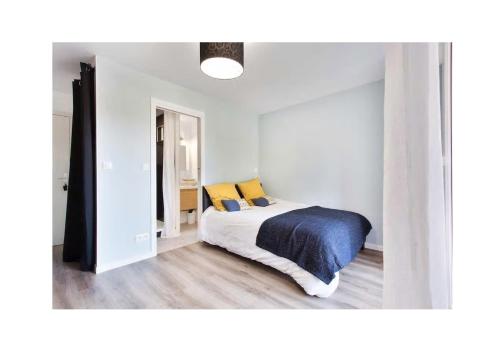 um quarto com uma cama com lençóis azuis e almofadas amarelas em Appartement Contemporain proche Météo, Basso Cambo, EDF, Airbus & Thales em Toulouse