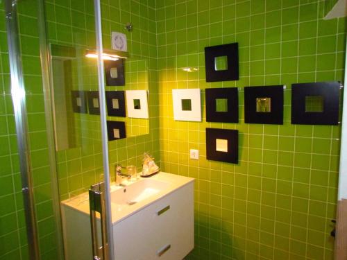 a green tiled bathroom with a sink and a mirror at Casa da Rua Nova in Castelo de Vide