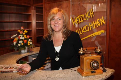 a woman sitting at a counter with a telephone at Kneipp-Kurhotel Steinle in Bad Wörishofen
