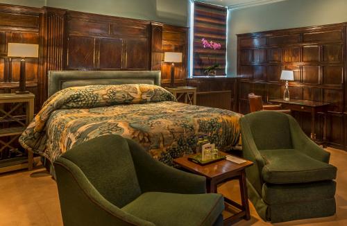 1 Schlafzimmer mit einem Bett, 2 Stühlen und einem Tisch in der Unterkunft The George Hotel of Stamford in Stamford