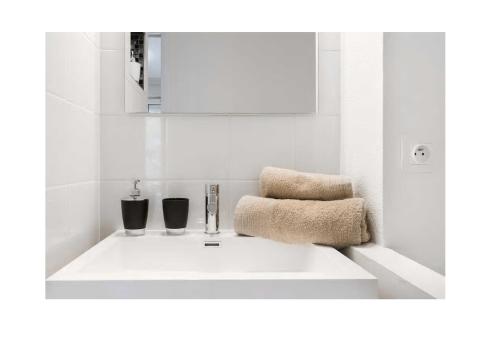 La salle de bains est pourvue d'un lavabo blanc et de 2 verres. dans l'établissement Appartement Contemporain proche Météo, Basso Cambo, EDF, Airbus & Thales, à Toulouse