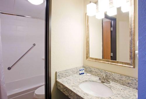a bathroom with a sink and a mirror and a toilet at AmericInn by Wyndham Alexandria in Alexandria