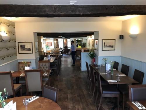 a dining room with tables and chairs and a person in the doorway at The Black Swan Inn in Norwich