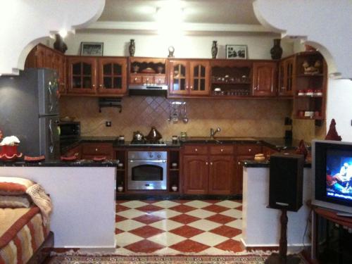 a kitchen with wooden cabinets and a tv in it at Aglou plage Grande Maison de Caractere tout confort les pieds dans l'eau in Aglou