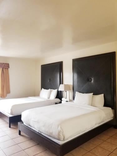 two beds in a hotel room with white sheets at Casa Bella Inn Downtown LA in Los Angeles