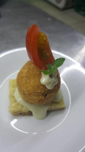 a white plate with a sandwich with a tomato on it at Alto Verde Suite & Apart in Termas de Río Hondo