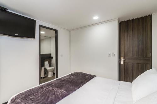 a bedroom with a bed and a tv on the wall at Hotel Express 53 in Bogotá