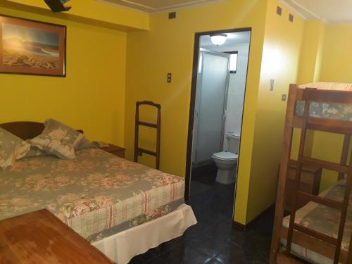 a bedroom with a bed and a bathroom with a toilet at Hotel Aymara in Calama