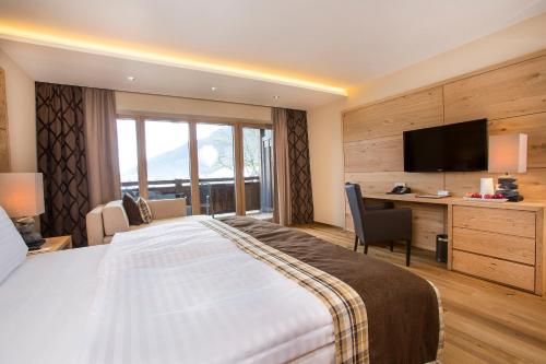 a hotel room with a bed and a desk and a television at Das gemütliche Dorfhotel Kaltenhauser in Hollersbach im Pinzgau