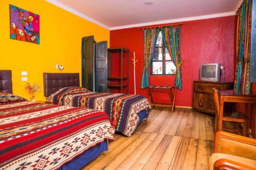 two beds in a room with red and yellow walls at Hostal Riviera Sucre in Otavalo