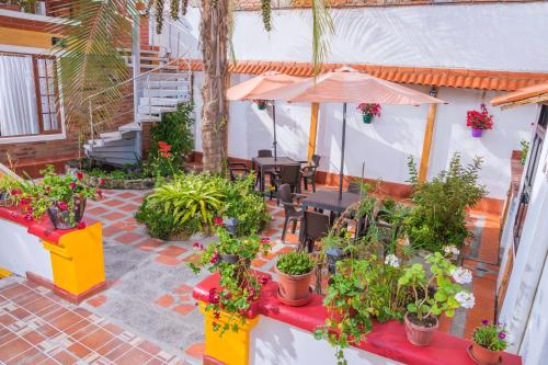 a patio with plants and tables and an umbrella at Hostal Riviera Sucre in Otavalo