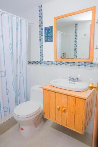 a bathroom with a toilet and a sink and a mirror at Hostal Riviera Sucre in Otavalo