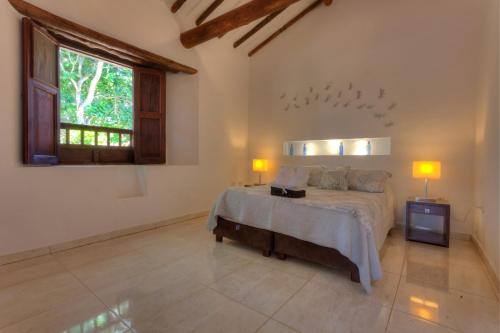 a bedroom with a bed with two lamps and a window at Casa Bari La Antigua in Barichara