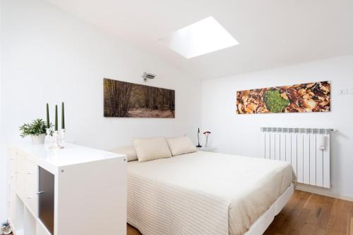 a white bedroom with a bed and paintings on the wall at La Maison del Capestrano in Milan