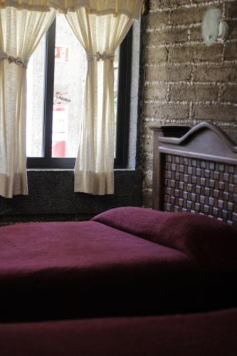 a bedroom with a bed and a window with curtains at Hotel y Cabañas una Cosita de Zacatlán in Zacatlán