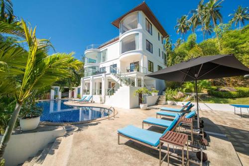 a building with chairs and an umbrella next to a pool at White Stone - Luxurious Sunset View 4 Bed Pool Villa in Nathon