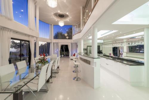a dining room with white chairs and tables and windows at White Stone - Luxurious Sunset View 4 Bed Pool Villa in Nathon