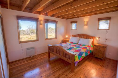 a bedroom with a wooden bed and two windows at Mopoke in Dinner Plain