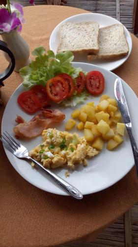 a plate of food with tomatoes and bread on a table at Tulip Resort Pai in Pai