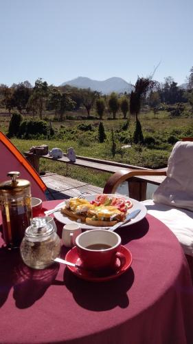 a table with a plate of food and a cup of coffee at Tulip Resort Pai in Pai