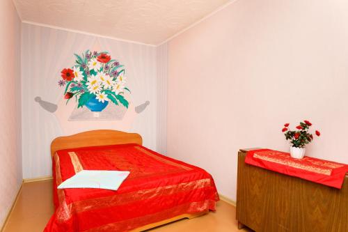 a room with a bed with a vase of flowers on the wall at Apartments on Chelyuskintsev in Yekaterinburg